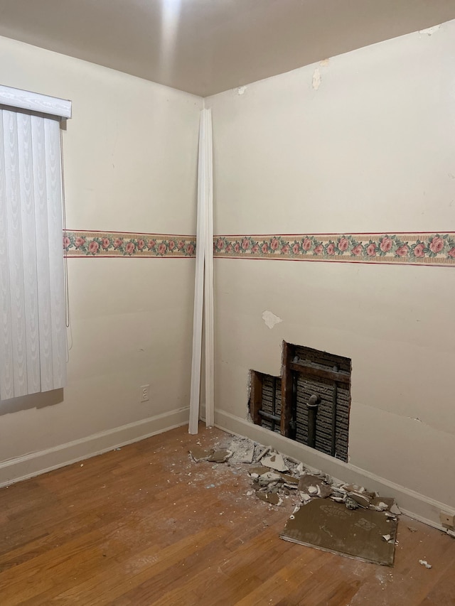 unfurnished living room featuring a fireplace, wood finished floors, and baseboards