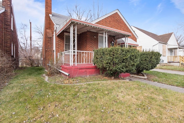 bungalow-style house featuring covered porch and a front yard