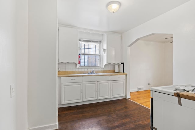 kitchen with sink, white cabinetry, dark wood-type flooring, and tasteful backsplash