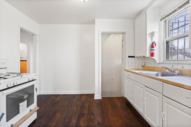 kitchen featuring white range with gas stovetop, white cabinets, dark wood-type flooring, and sink