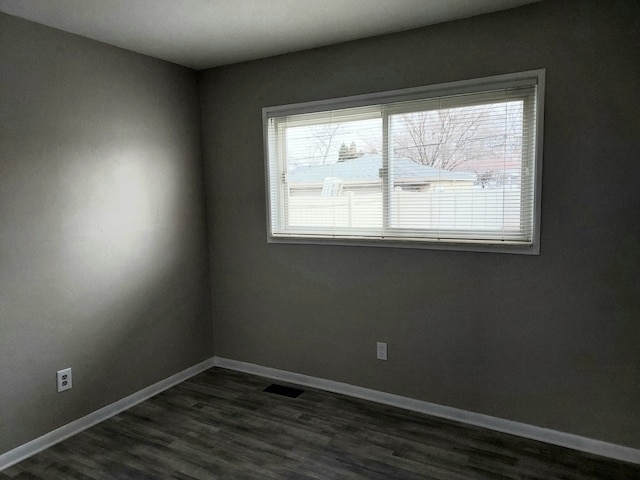 spare room featuring dark wood-type flooring and a healthy amount of sunlight