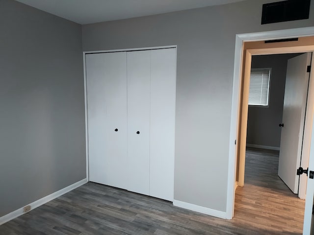 unfurnished bedroom with a closet and dark wood-type flooring