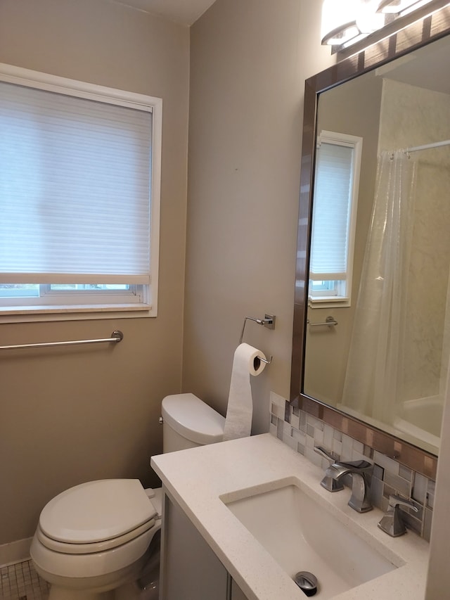 bathroom with vanity, tasteful backsplash, toilet, and a wealth of natural light