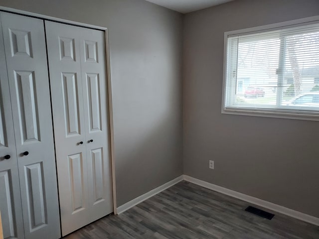 unfurnished bedroom featuring a closet and dark wood-type flooring