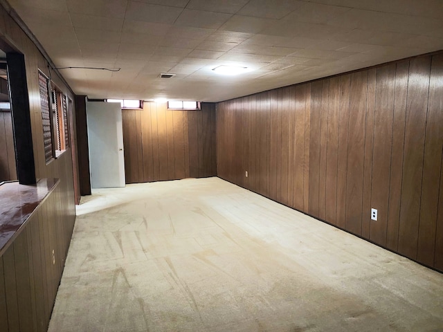 basement featuring light colored carpet and wooden walls