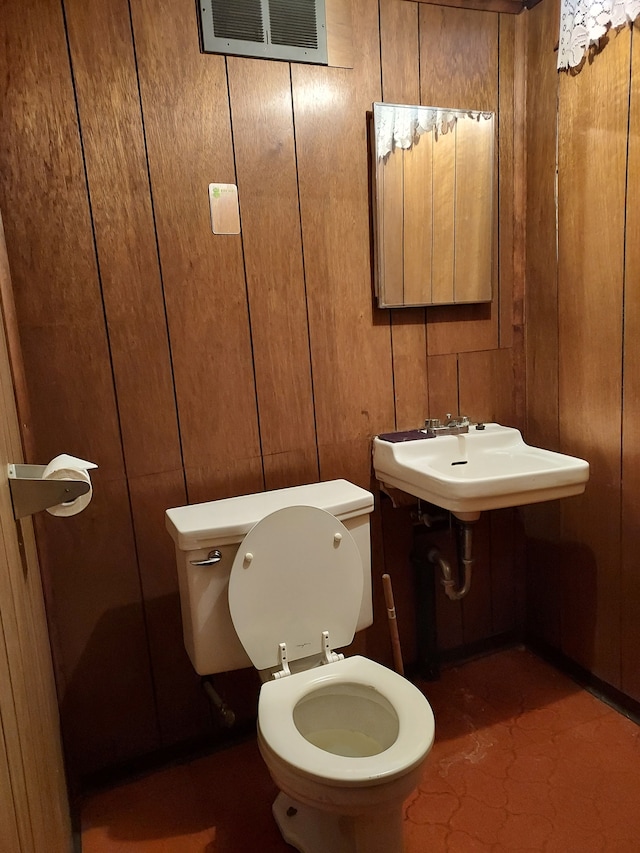 bathroom featuring toilet and wooden walls