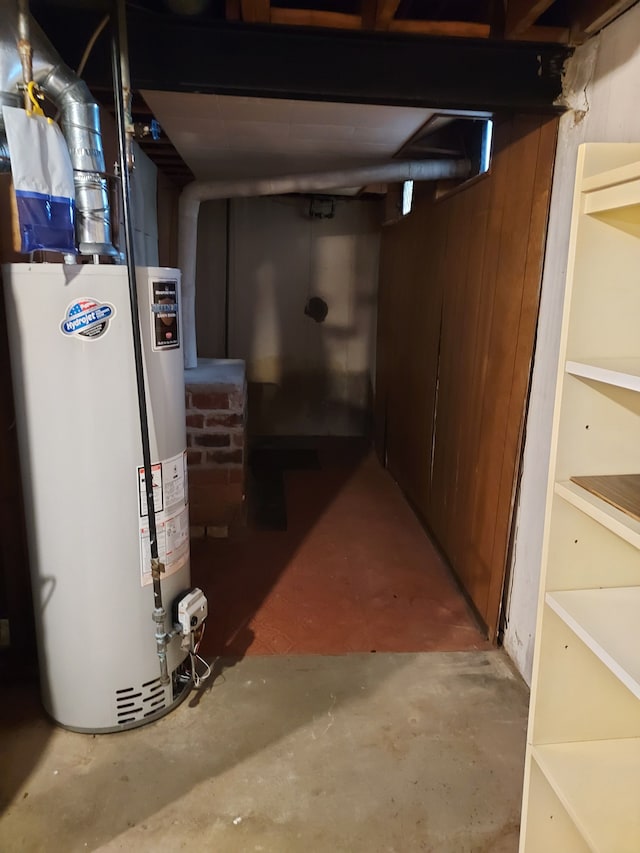 basement with gas water heater and wooden walls