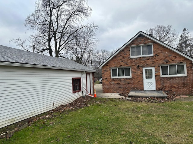 back of property featuring a lawn and brick siding