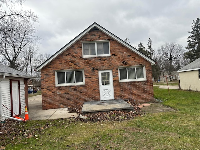 rear view of house featuring a lawn and brick siding