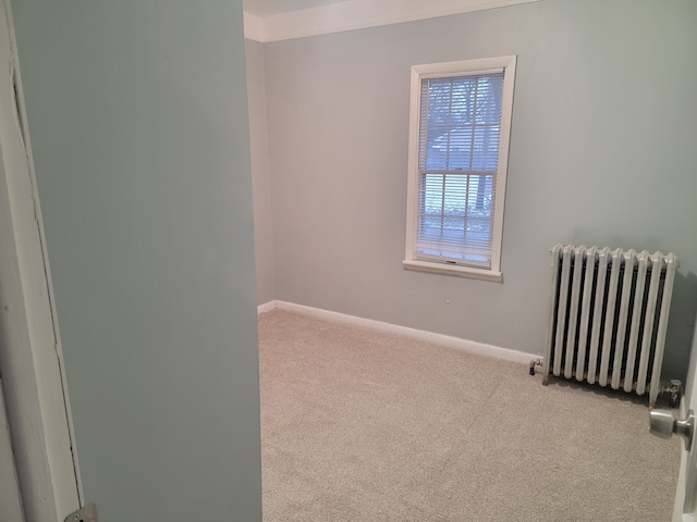 unfurnished room featuring carpet flooring, baseboards, and radiator heating unit