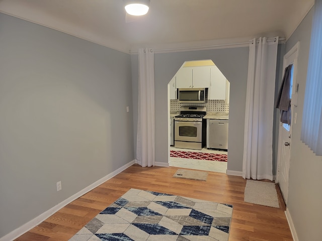 kitchen with light wood-style flooring, baseboards, tasteful backsplash, and appliances with stainless steel finishes