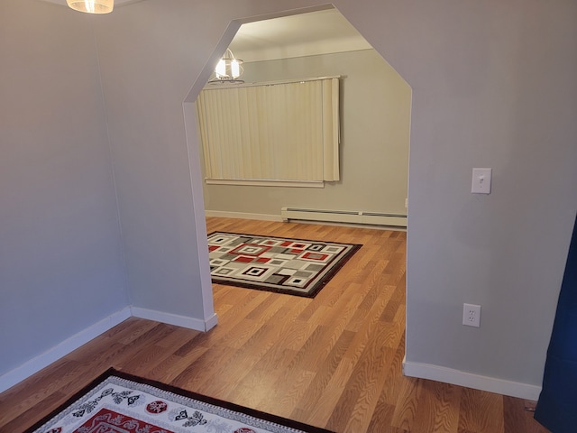 hall featuring wood finished floors, baseboards, and a baseboard radiator