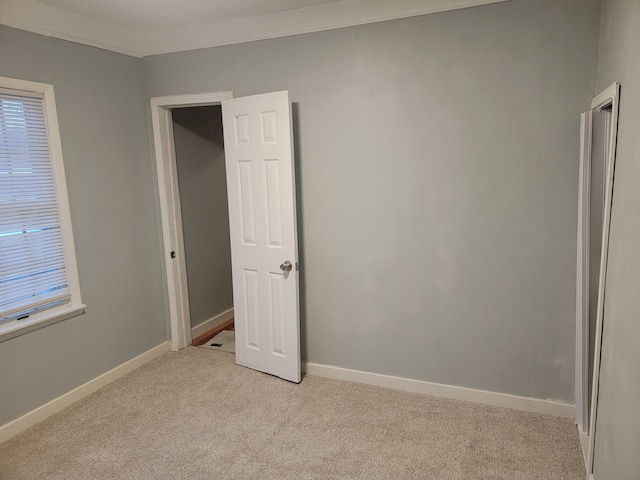 unfurnished room featuring baseboards, light colored carpet, and ornamental molding