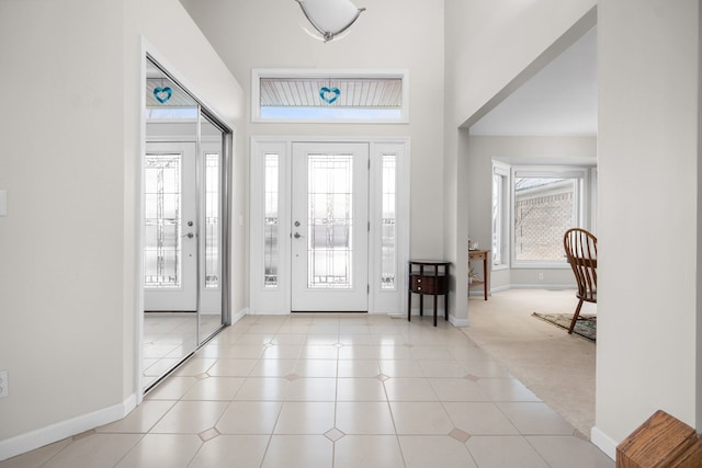 foyer featuring a healthy amount of sunlight, light carpet, and a high ceiling