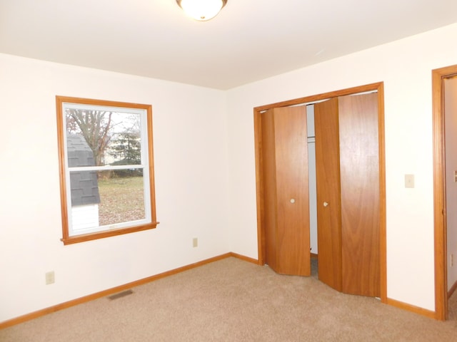 unfurnished bedroom featuring light colored carpet and a closet