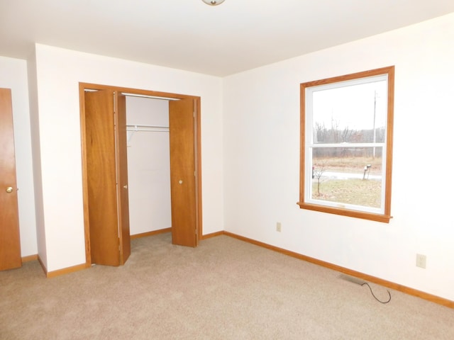 unfurnished bedroom featuring light carpet and a closet