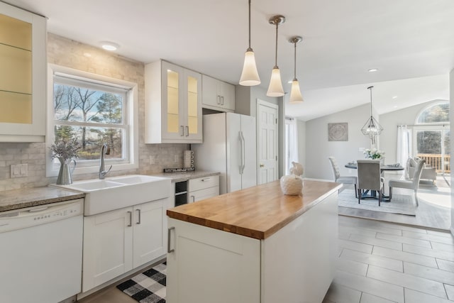 kitchen featuring white appliances, white cabinets, sink, vaulted ceiling, and a kitchen island