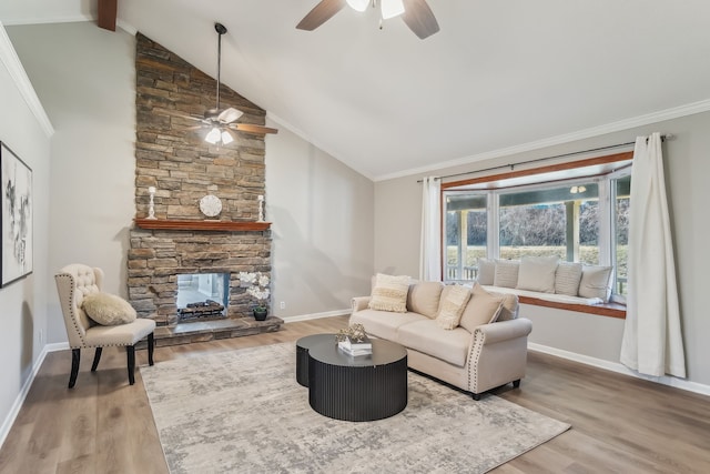 living room featuring ornamental molding, ceiling fan, hardwood / wood-style flooring, vaulted ceiling with beams, and a stone fireplace