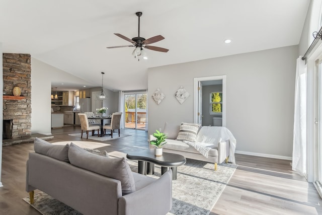 living room featuring a fireplace, hardwood / wood-style flooring, ceiling fan, and lofted ceiling