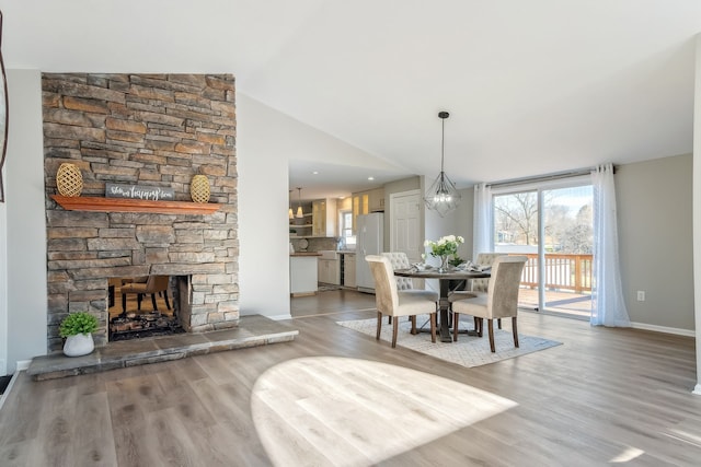 dining room with a fireplace, wood-type flooring, and lofted ceiling