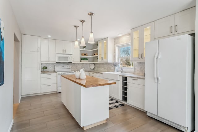 kitchen featuring a center island, butcher block countertops, decorative light fixtures, white appliances, and white cabinets