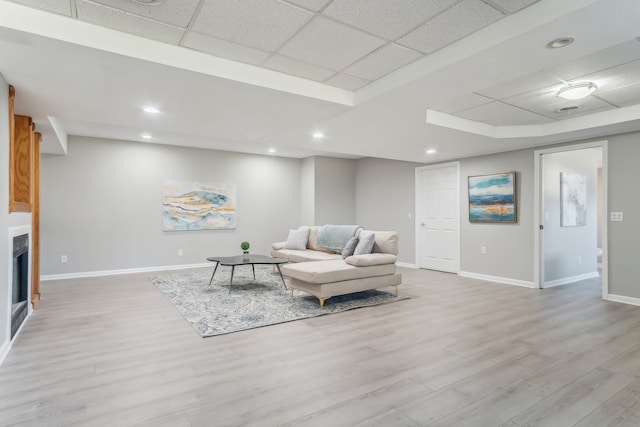 living room featuring a paneled ceiling and light hardwood / wood-style flooring