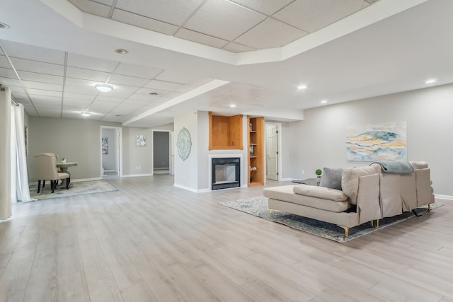 living room with a drop ceiling and light wood-type flooring