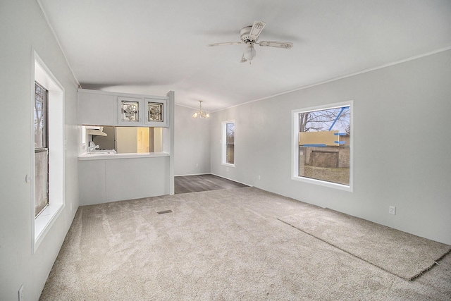 unfurnished living room with carpet, ceiling fan with notable chandelier, and crown molding