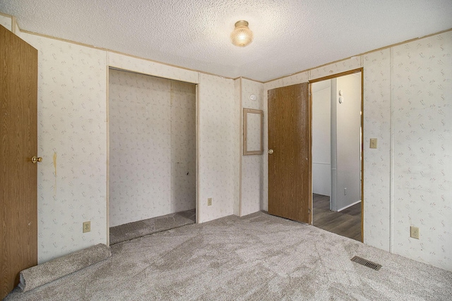 unfurnished bedroom featuring dark colored carpet and a textured ceiling