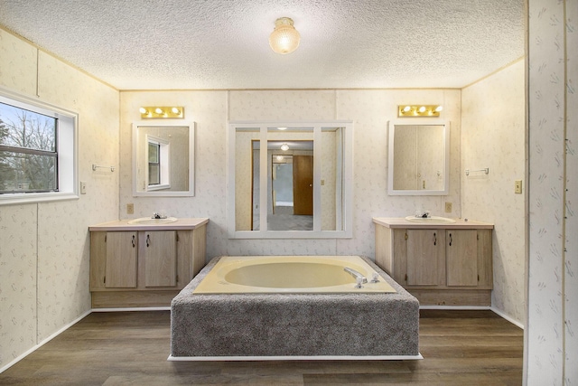 bathroom with vanity, a textured ceiling, hardwood / wood-style flooring, and a tub