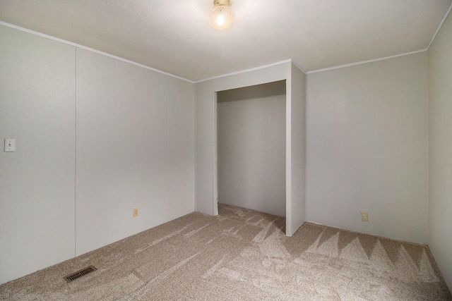 unfurnished bedroom featuring carpet flooring, crown molding, and a closet