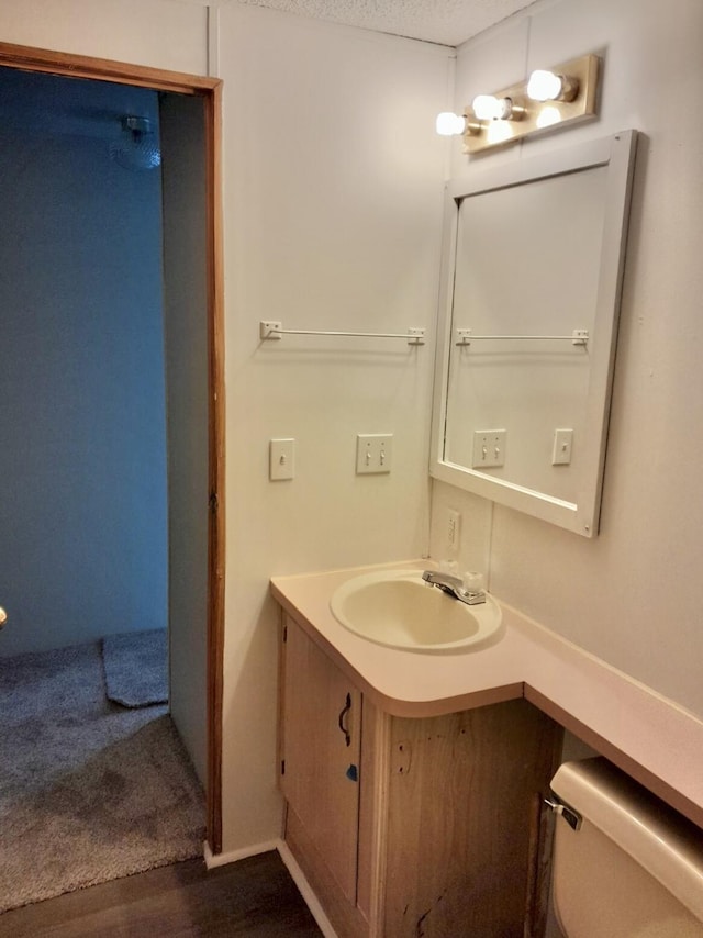 bathroom with hardwood / wood-style floors, vanity, a textured ceiling, and toilet