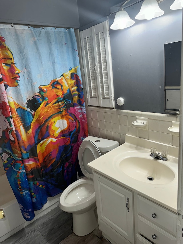 full bathroom featuring vanity, hardwood / wood-style flooring, toilet, tile walls, and shower / tub combo