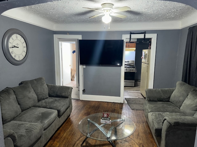 living room with hardwood / wood-style flooring, ceiling fan, and a textured ceiling