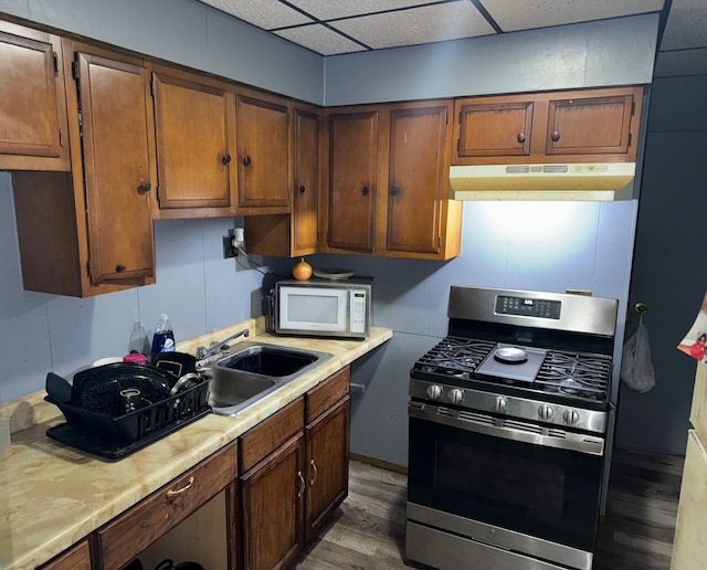 kitchen with hardwood / wood-style flooring, a drop ceiling, stainless steel range with gas cooktop, and sink