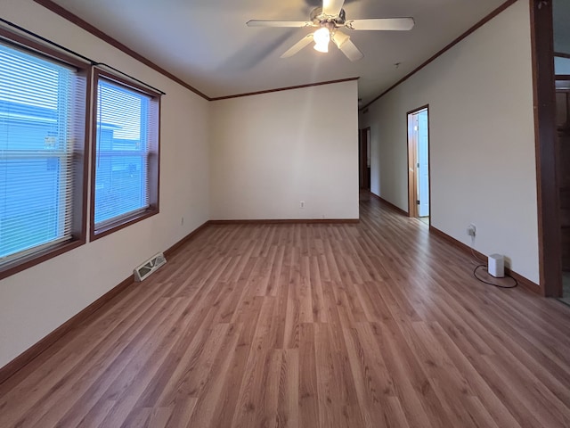 empty room with ceiling fan, light wood-type flooring, and ornamental molding