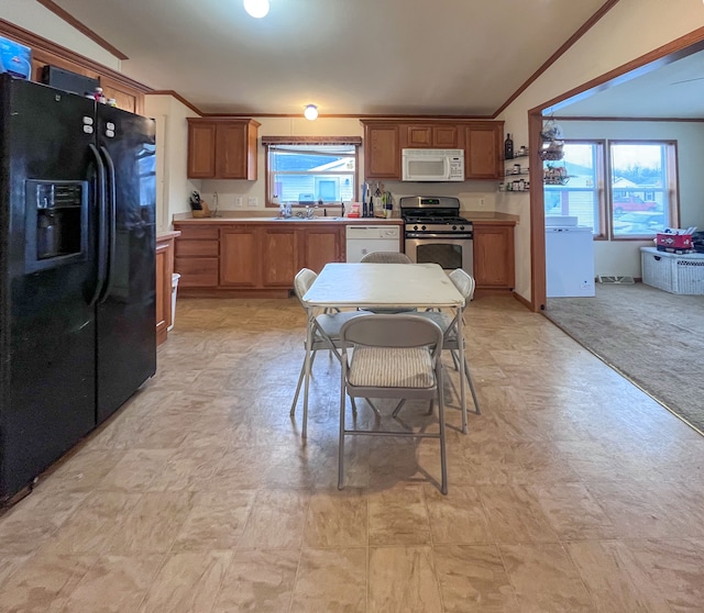 kitchen with vaulted ceiling, light colored carpet, white appliances, and ornamental molding