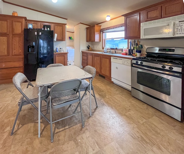 kitchen featuring lofted ceiling, sink, white appliances, and washer / dryer