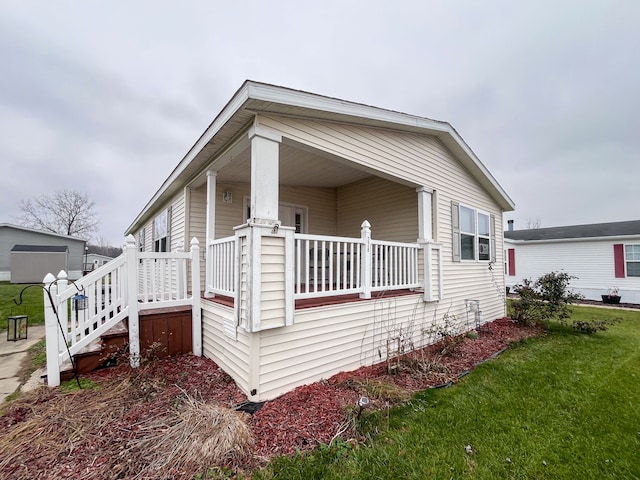 view of side of home featuring a lawn and covered porch