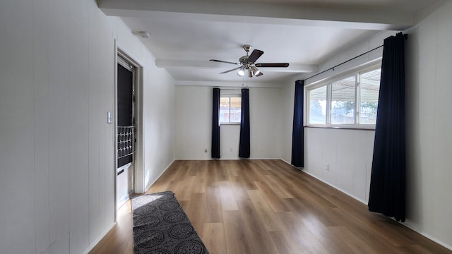 unfurnished room with beamed ceiling, hardwood / wood-style flooring, ceiling fan, and wood walls