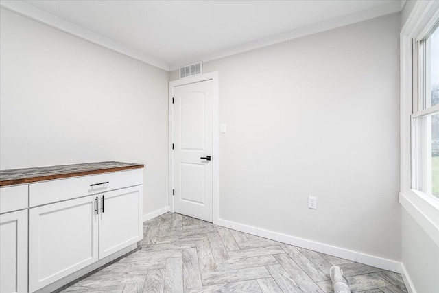 interior space with plenty of natural light, crown molding, and light parquet flooring