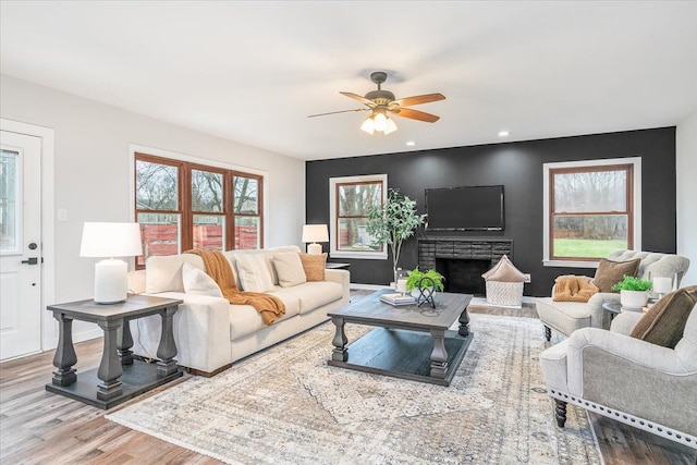 living room featuring a fireplace, hardwood / wood-style flooring, a wealth of natural light, and ceiling fan