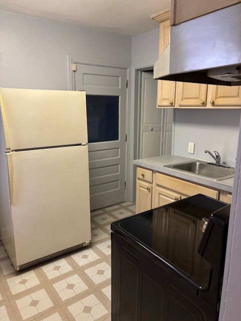 kitchen with white fridge, black range with electric stovetop, sink, and exhaust hood