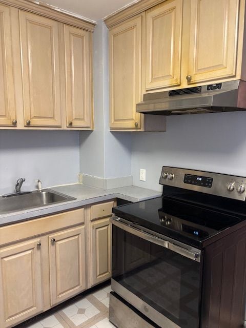 kitchen featuring light brown cabinetry, electric range, sink, and light tile patterned floors