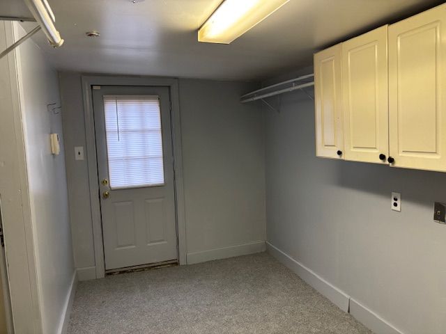 laundry room featuring light colored carpet and cabinets