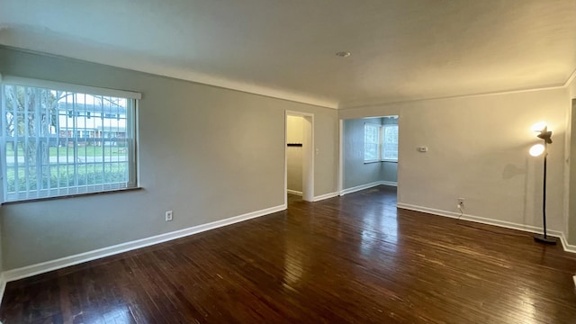 empty room with a wealth of natural light and dark hardwood / wood-style floors