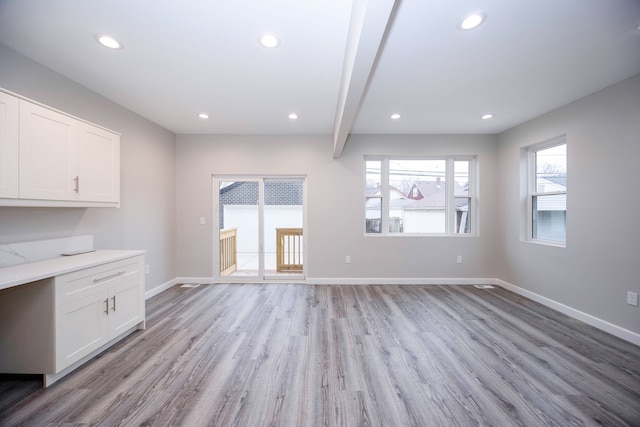 unfurnished living room with beam ceiling and light hardwood / wood-style floors