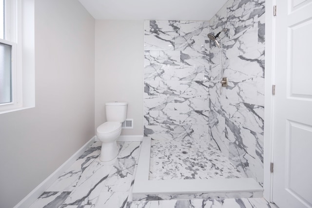 bathroom featuring tiled shower and toilet