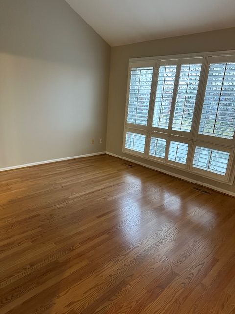 spare room featuring dark hardwood / wood-style floors and vaulted ceiling