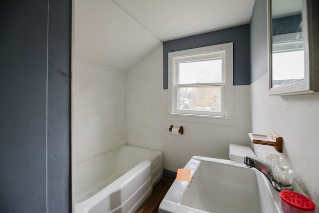 bathroom with a bathtub, lofted ceiling, and sink